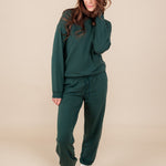 Modal posing in Women's Jogger Pant in Cypress color under similar color sweatshirt on a beige background