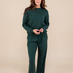 Woman wearing Women's Sweatpants in Cypress color under similar color women's sweatshirt on a beige background
