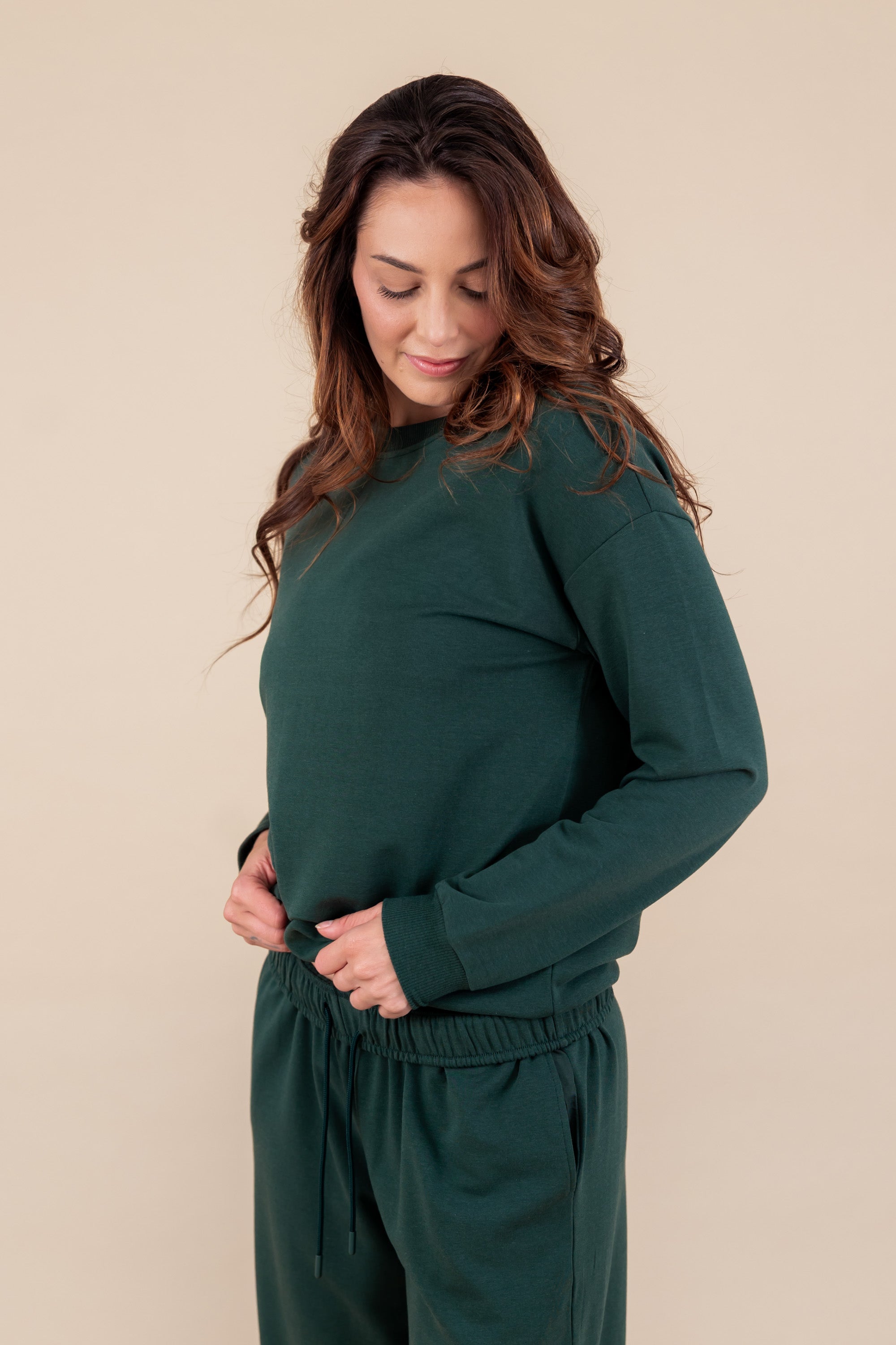 Modal posing in Women's Jogger Pant in Cypress color under similar color sweatshirt on a beige background