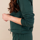 Side view of Modal wearing Women's Jogger Pant in Cypress color under similar color sweatshirt on a beige background