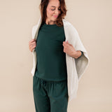 Woman wearing Women's Sweatpants in Cypress color with beige color sweater over her shoulders under similar color women's sweatshirt on a beige background