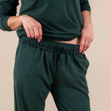 Close up of Modal wearing Women's Sweatpants in Cypress color under similar color women's sweatshirt on a beige background