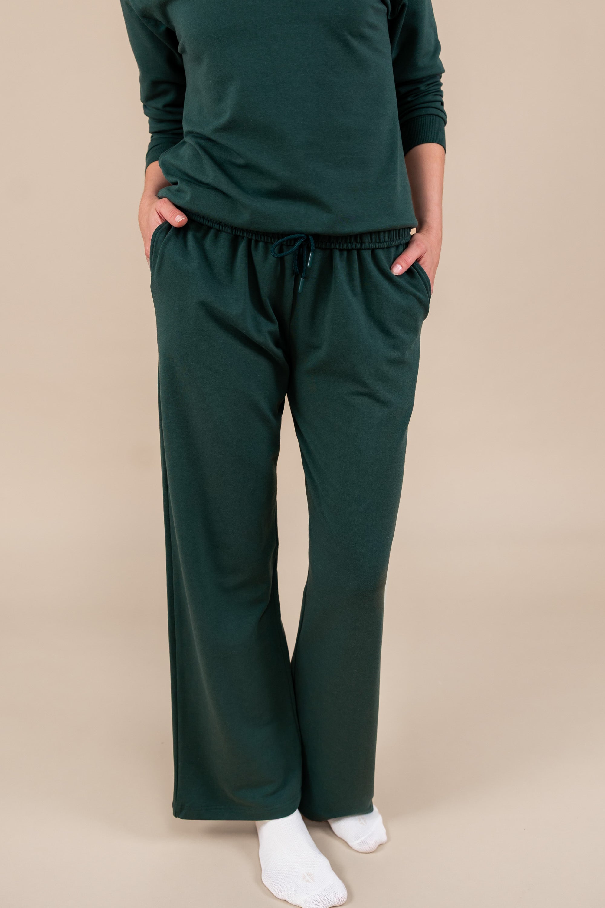 Modal wearing Women's Sweatpants in Cypress color under similar color women's sweatshirt on a beige background
