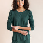 Woman smiling with her eyes looking to the side pulling up her sleeve in jogger pajama set in cypress
