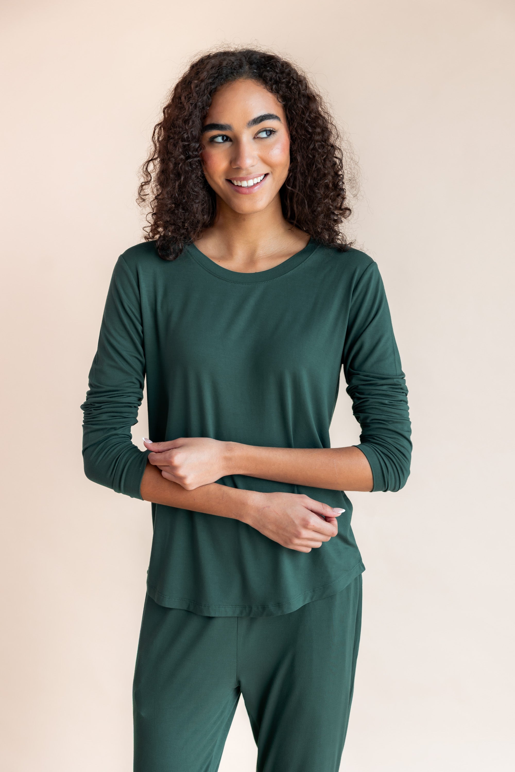 Woman smiling with her eyes looking to the side pulling up her sleeve in jogger pajama set in cypress