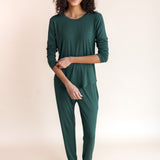 Woman soft smiling pulling her sleeve up in jogger pajama set in cypress color