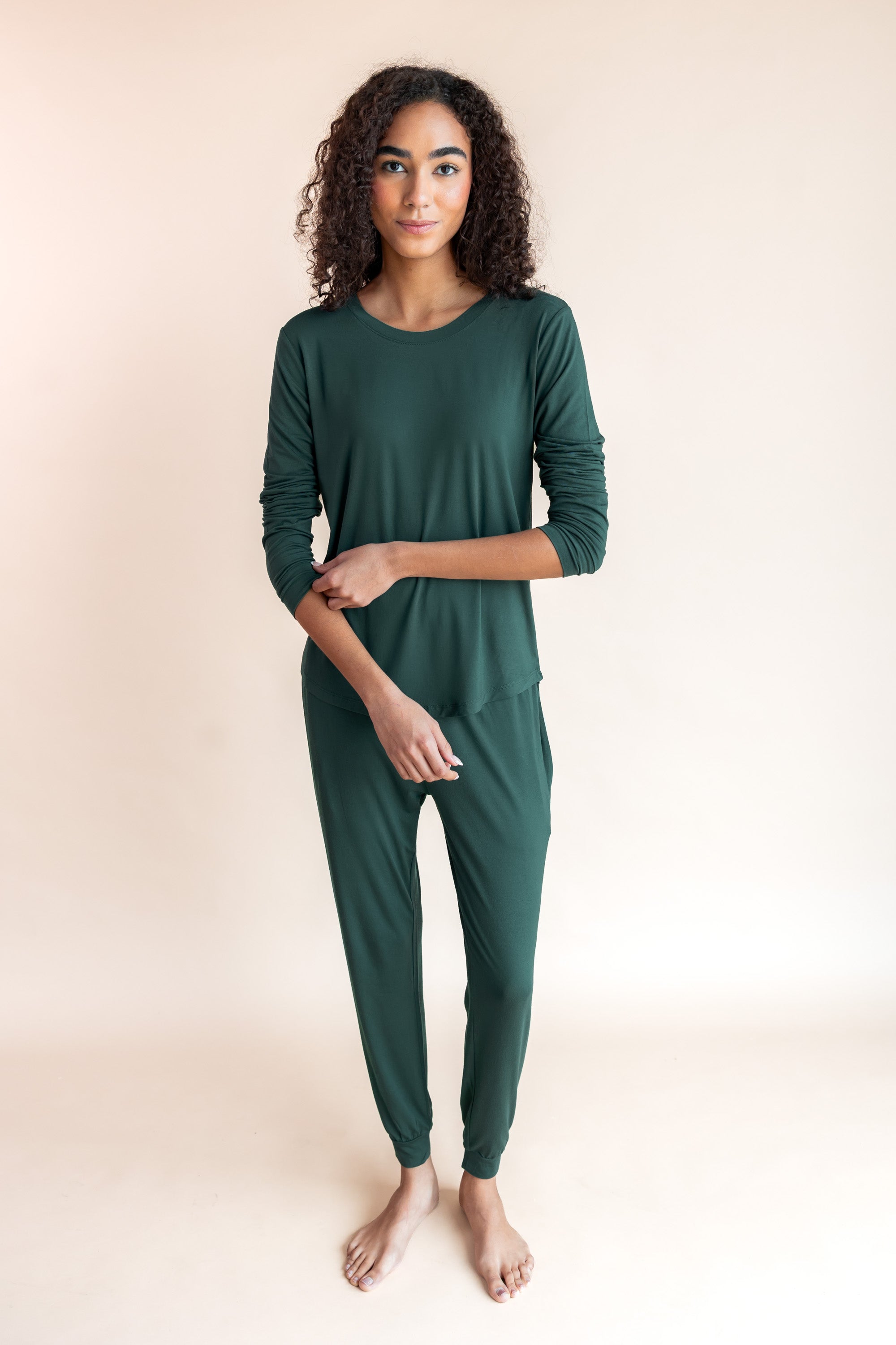 Woman soft smiling pulling her sleeve up in jogger pajama set in cypress color
