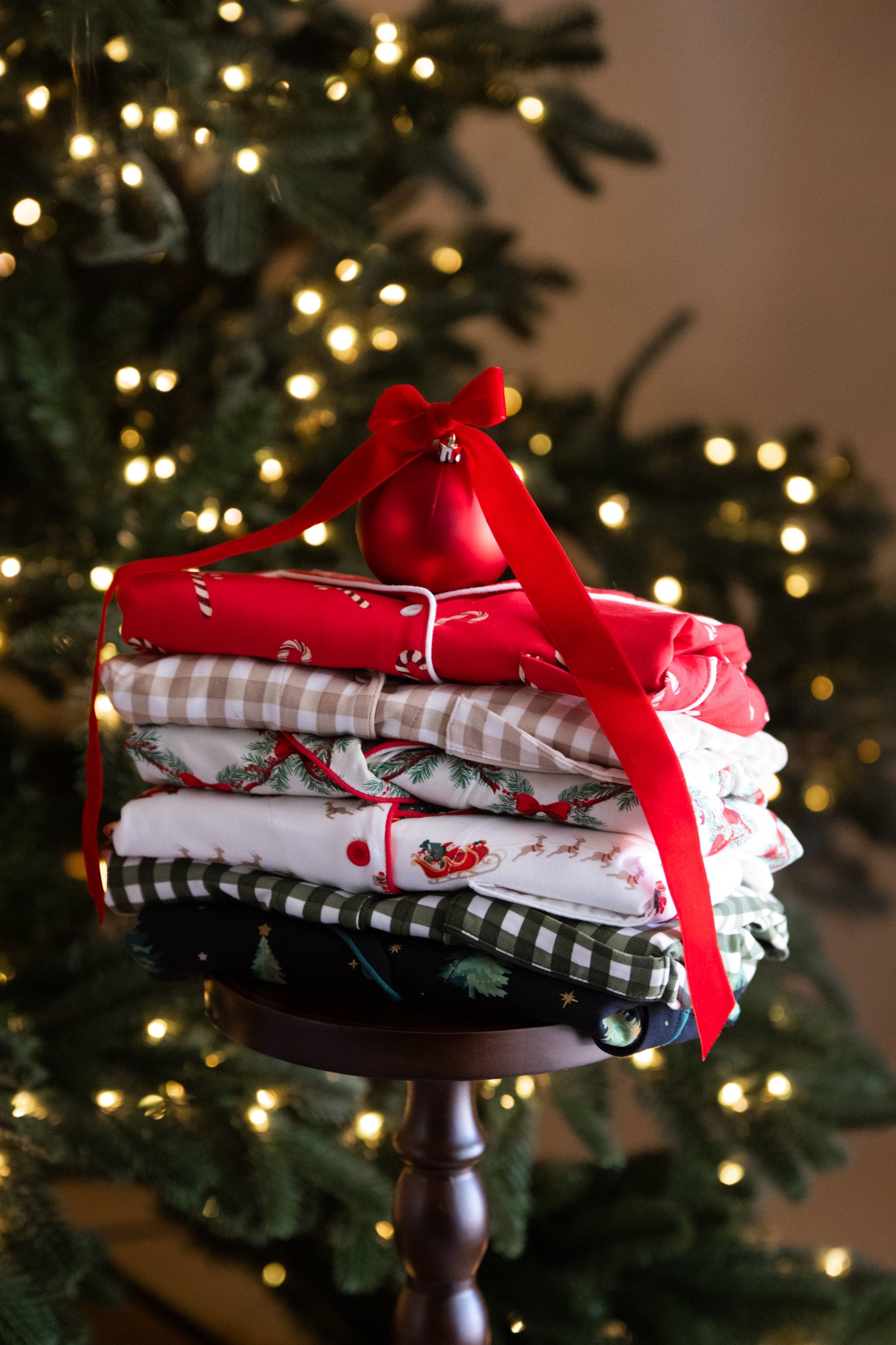 Stack of folded fabric with a red ribbon against a Christmas tree background