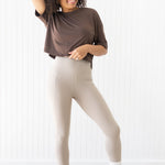 Smiling model wearing the Flex Leggings in Bisque paired with a crop