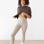 Model raising crop top to show the waist of the Bamboo Flex Women’s Leggings in Bisque
