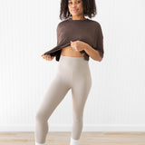 Model raising crop top to show the waist of the Bamboo Flex Women’s Leggings in Bisque
