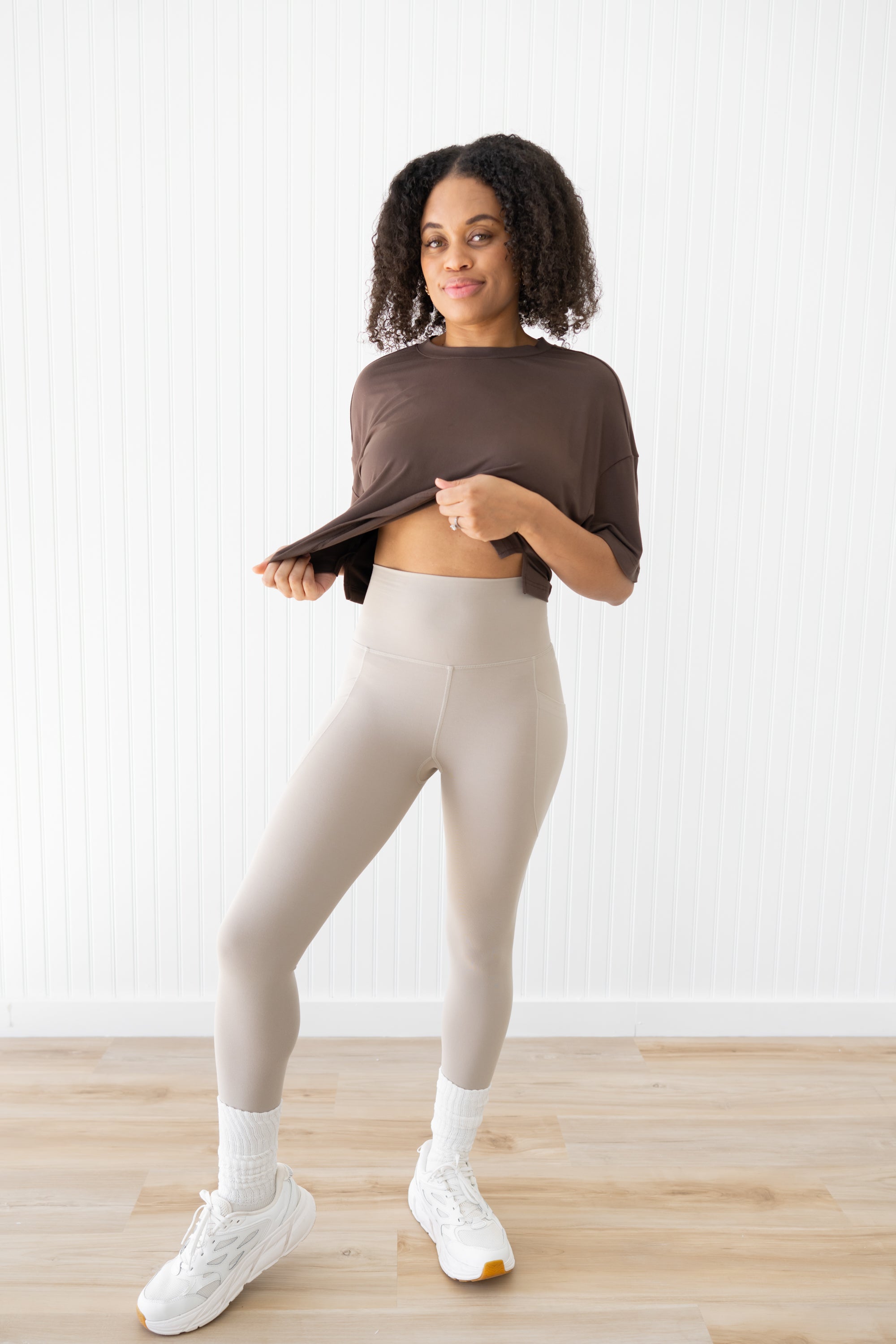 Model raising crop top to show the waist of the Bamboo Flex Women’s Leggings in Bisque
