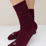 Burgundy socks worn by a person on a white surface with a beige background