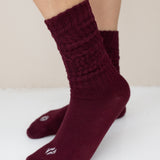 Burgundy socks worn by a person on a white surface with a beige background