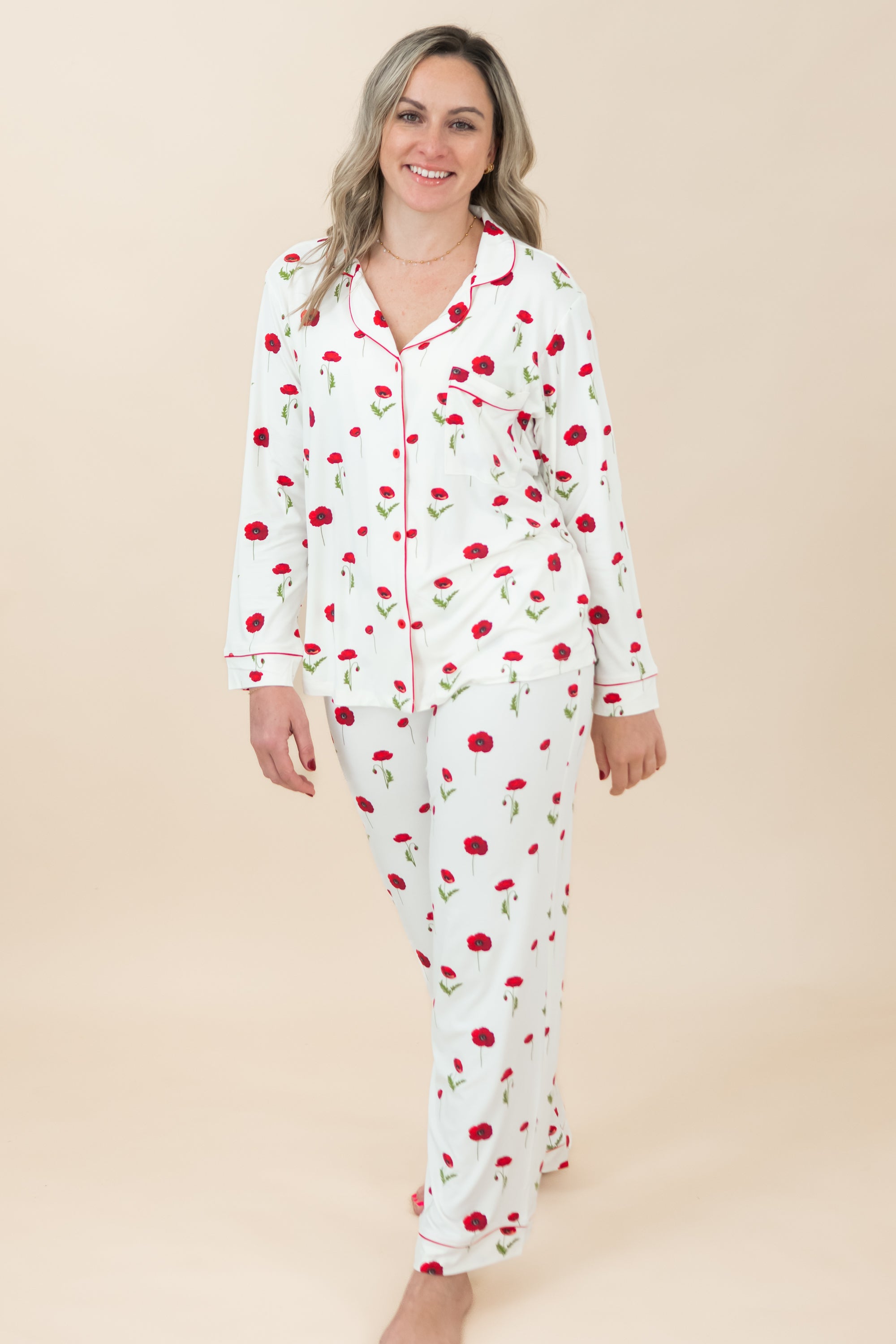 Woman wearing a white pajama set with red floral pattern on a beige background