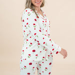 Woman wearing a white pajama set with red floral patterns on a beige background