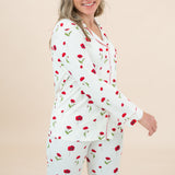 Woman wearing a white pajama set with red floral patterns on a beige background