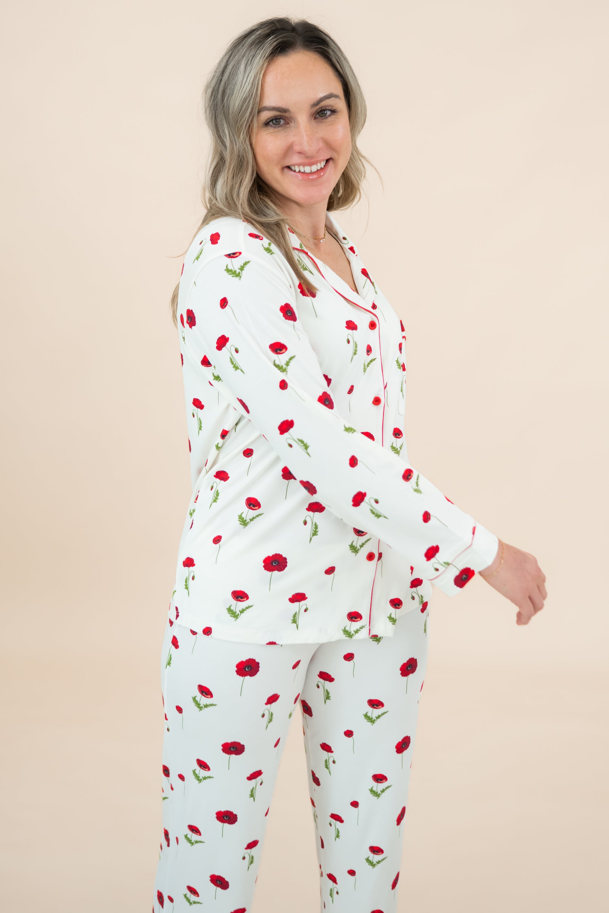 Woman wearing a white pajama set with red floral patterns on a beige background