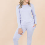 Woman wearing a light purple long-sleeve top and pants on a beige background
