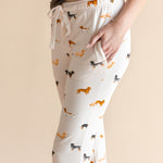 Model showcasing the pockets of Women's Lounge Pants in Dachshund  under a brown camisole on a beige background