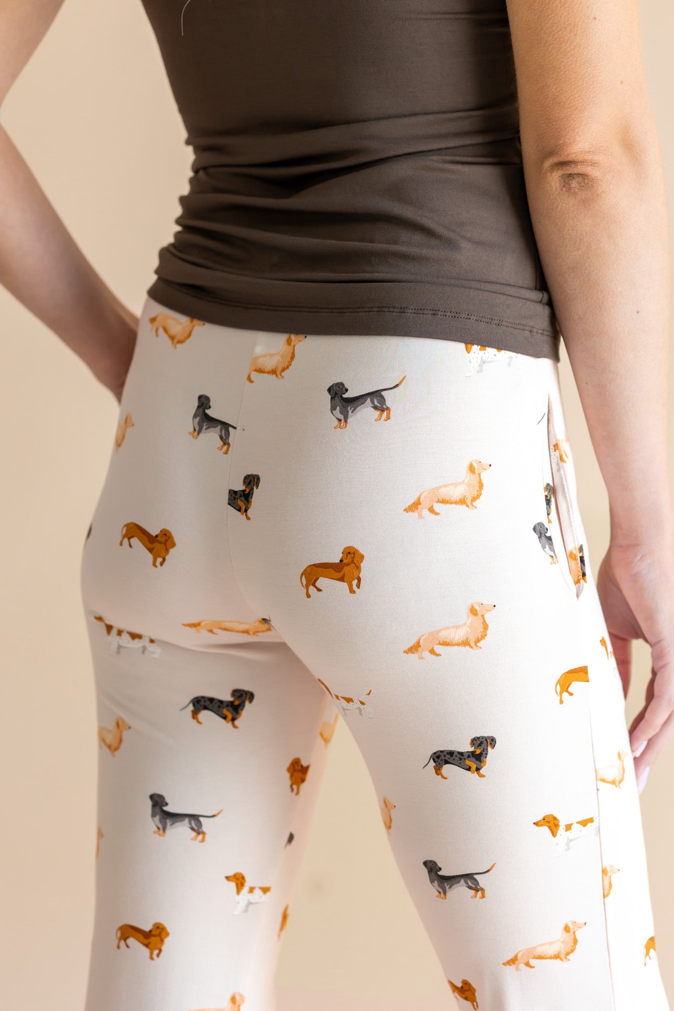 Model showing the back of Women's Lounge Pants in Dachshund print under a brown camisole on a beige background