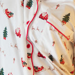 Close up of a white button up pajama top with red piping and a christmas pattern
