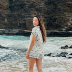 Woman standing on a beach with ocean and cliffs in the background wearing Women's Short Sleeve Pajama Set in Dew Surf 
