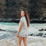 Woman standing on a beach with ocean and cliffs in the background wearing Women's Short Sleeve Pajama Set in Dew Surf 