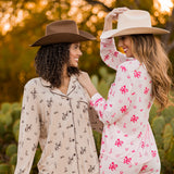 Two women wearing western patterned pajamas outdoors with a blurred natural background