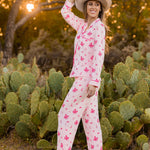 Smiling model standing in front of cacti wearing the Long-Sleeved Women's Pajama Set in Disco Cowgirl with a neutral colored western hat