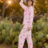 Smiling model standing in front of cacti wearing the Long-Sleeved Women's Pajama Set in Disco Cowgirl with a neutral colored western hat