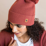 Modal wearing Chunky Knit Adult Pom in ember over white t-shirt and chunky knit women's  cardigan in ember on a beige background