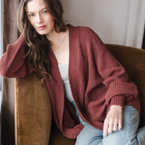 Woman leaning on the chair armrest in jeans and an oversized cardigan in ember
::: Model is 5'8" wearing size XS ///

