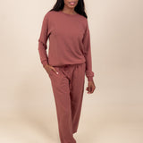 Woman posing in Women's Jogger Pant in Ember color and a similar color sweatshirt on a beige background