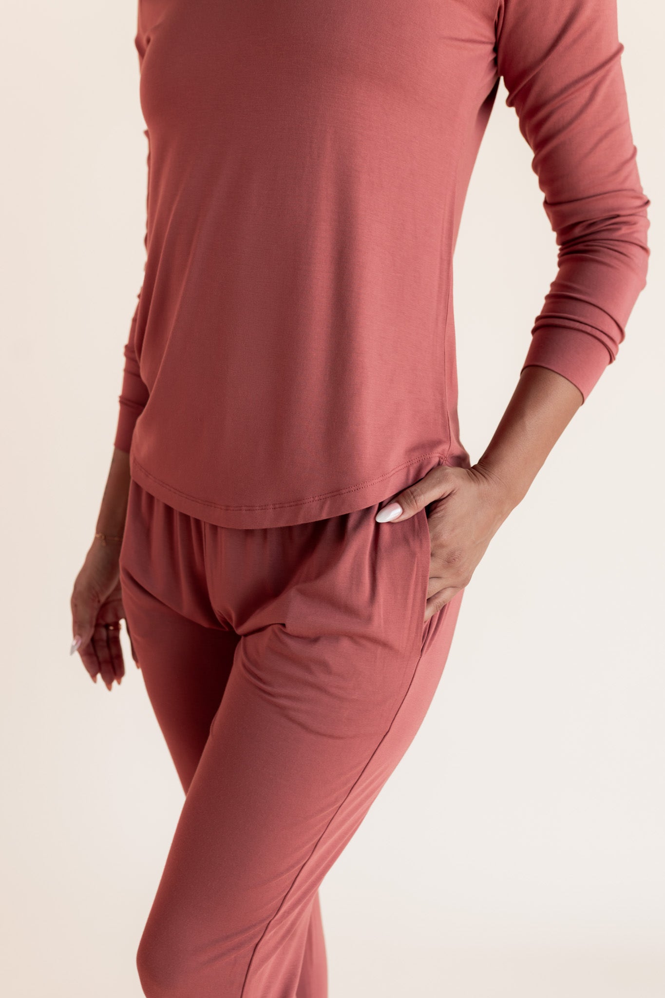 Woman modeling a jogger pajama set in a terracotta color , close up on pocket detail on pant