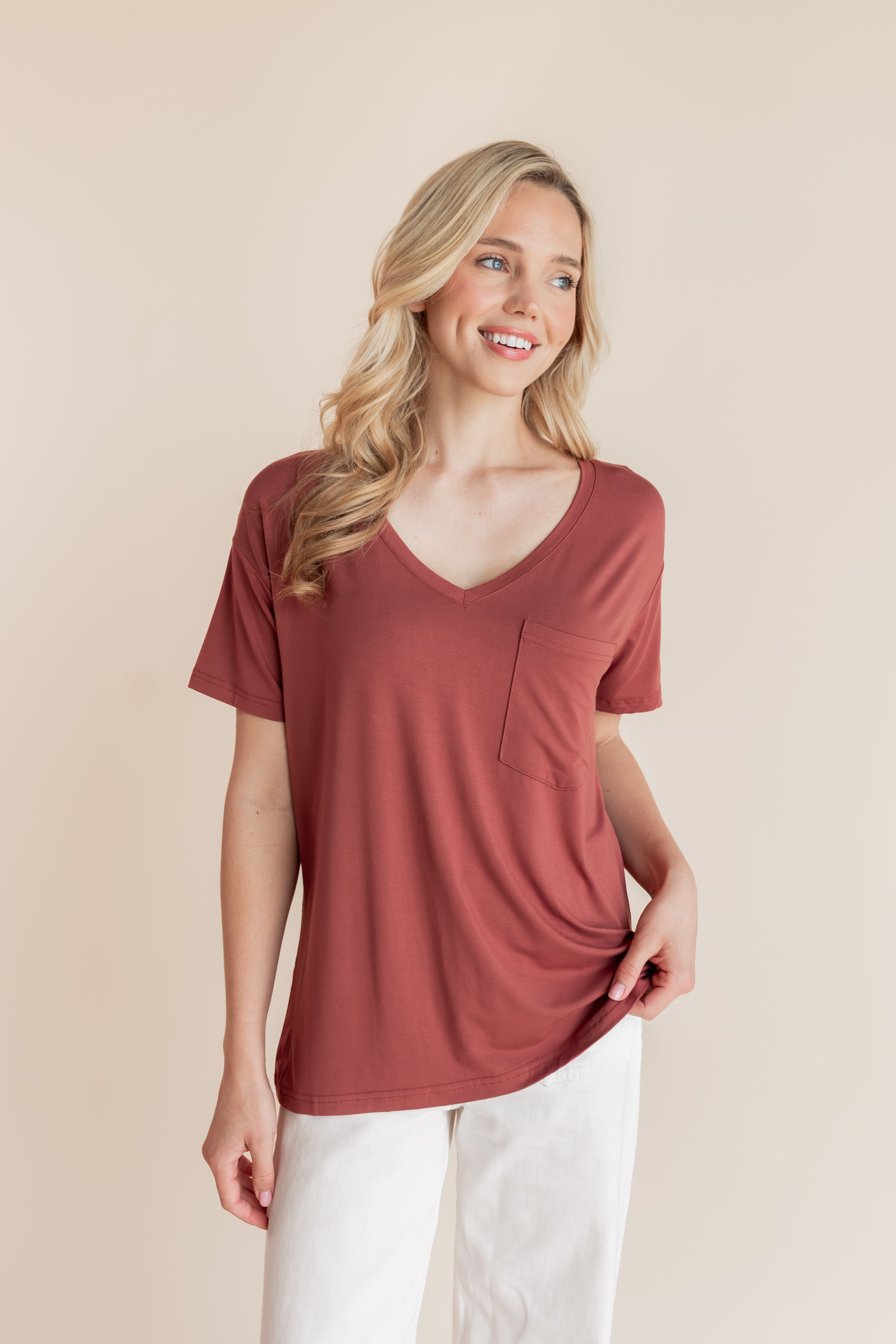 Model wearing Women's Oversized V-Neck Tee in Ember over white pants on a beige background