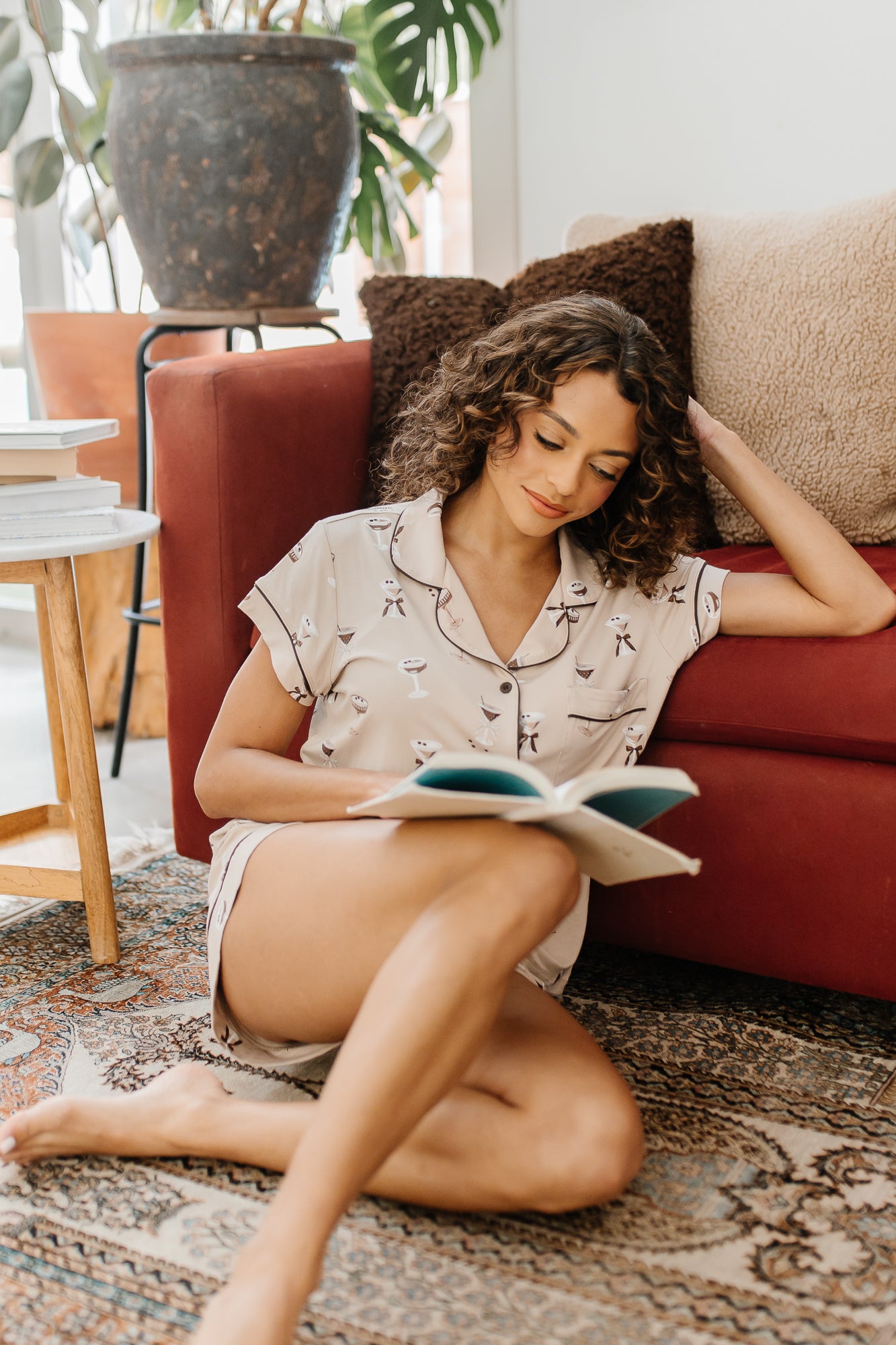 Model sitting on the floor reading a book wearing the Kyte Bamboo Women's Short Sleeve Pajama Set in Espresso Martini