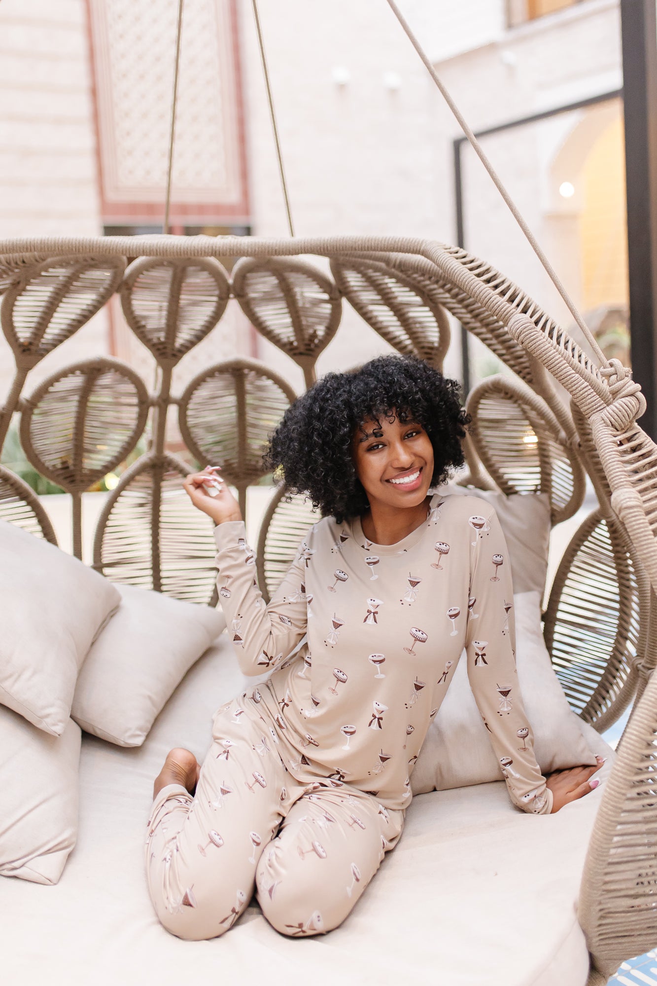Smiling model in a rattan chair wearing the Women's Jogger Set in Espresso Martini