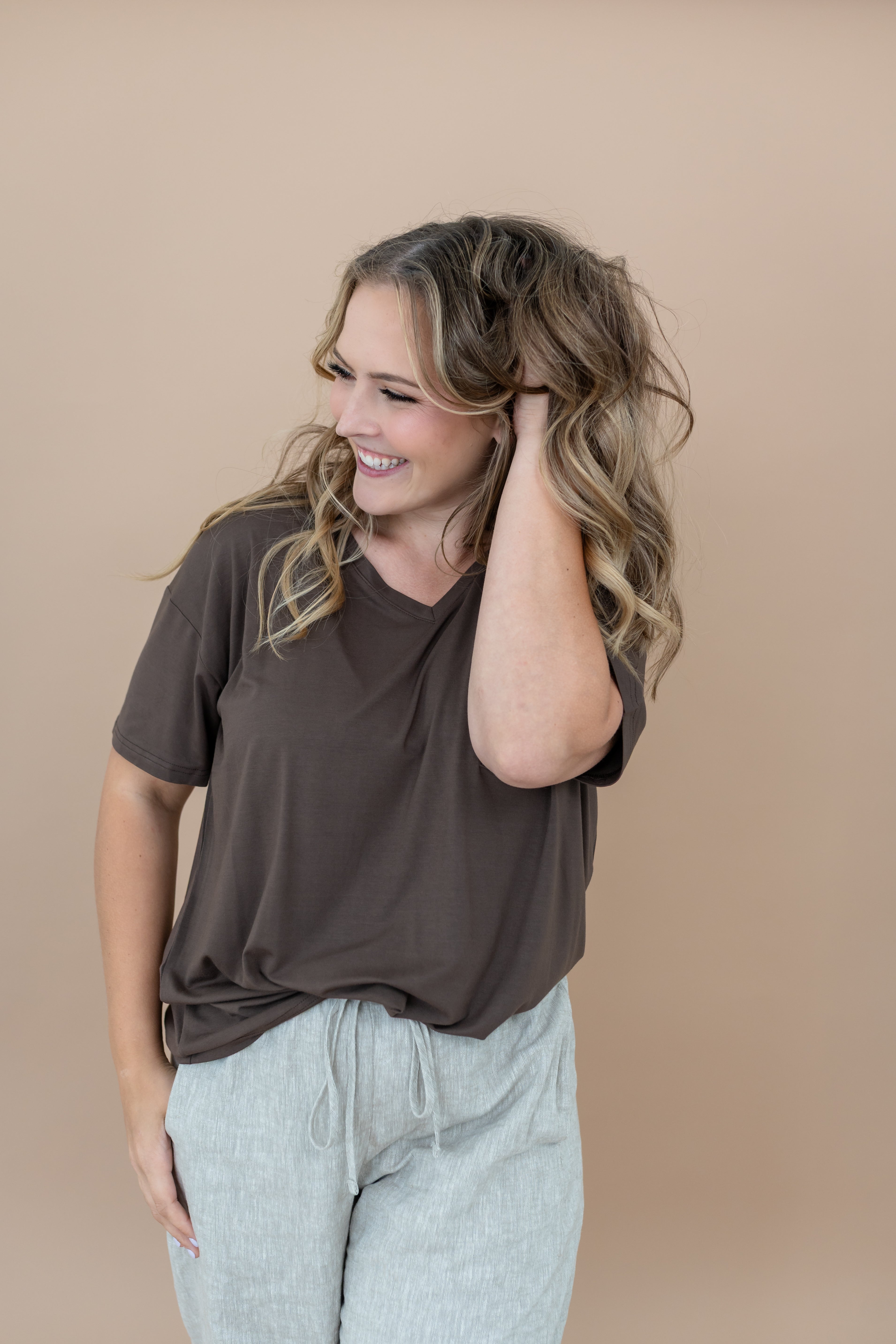 Model with hand in her hair, smiling to the side while wearing the Women's V Neck in Espresso 