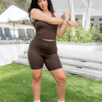 Female model standing in the grass in front of a house stretching wearing the Bamboo Flex High Rise Biker Short in Espresso and matching bra tank

::: Model is 5'9" wearing size L ///
