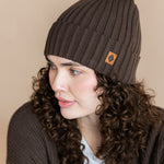 Modal wearing Chunky Knit Adult Ribbed Beanie in espresso over white t-shirt and chunky knit women's cardigan in espresso on a beige background
