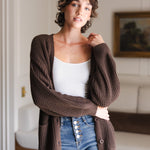 Modal standing in a living room wearing Chunky Knit Women's Waffle Cardigan in Espresso over white camisole and blue jeans
::: Model is 5'10" wearing size XS ///