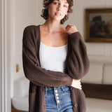 Modal standing in a living room wearing Chunky Knit Women's Waffle Cardigan in Espresso over white camisole and blue jeans
::: Model is 5'10" wearing size XS ///