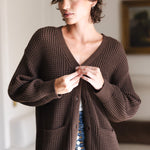 Modal buttoning Chunky Knit Women's Waffle Cardigan in Espresso over white camisole and blue jeans in a living room