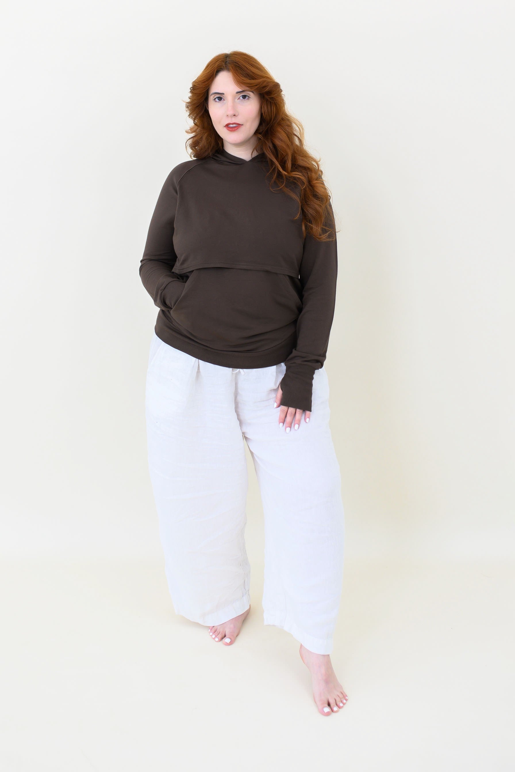 Female model wearing the Women's French Terry Nursing Hoodie in Espresso paired with white pants