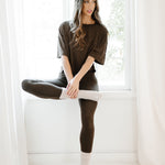 Female model sitting on a window sill wearing the Bamboo Flex Women’s Leggings in Espresso and short sleeve tee