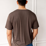 Man showing the back side of Men's Crew Neck Tee in Espresso and blue jeans in front of a white wall