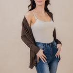 Model looking off to the side with the Women's French Terry Wrap Top in Espresso off one shoulder paired with a cami and jeans