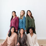 Models standing and sitting in a group wearing Women's Long Sleeve Pajama Sets in Burgundy, Atlantic, Fir, Latte, Espresso and Bisque