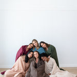 Models sitting together wrapped in Quilted Blankets 2.5 in Burgundy, Atlantic, Fir, Latte, Espresso and Bisque